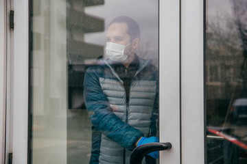 Male with mask and gloves leaving his home in quarantine time. Covid-19 outbreak themed image, 