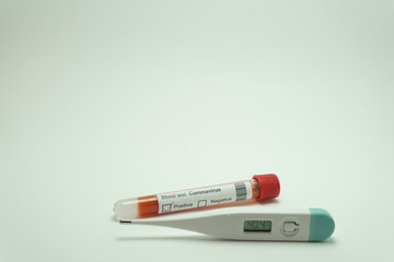 Obraz premium Blood test of the coronavirus with a thermometer. The blood tube is positive. The thermometer reads 40 degrees, a symptom of the 2019-nCov.