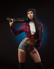Fototapeta premium the girl in a checked shirt on a dark background with a shotgun