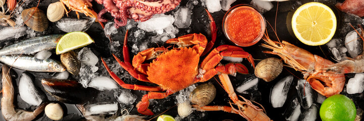 Crab with fish, shrimps, and caviar, overhead seafood panorama on a dark background