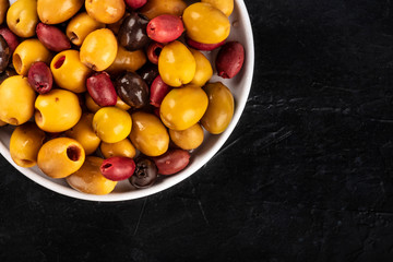 Olives variety. Black, green and red olives, shot from above on a dark background with a place for text