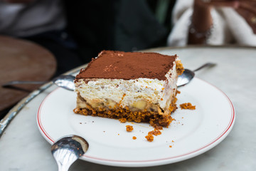 Banofeemisu close up, La Felicita, Paris, France. Beautiful close of a revisited Tiramisu on a white plate. Ingredients : Speculos, banana, mascarpone, cocoa powder. Delicious thick italian dessert.