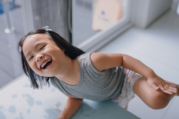 Asian girl with black hair aged 2-4 years old. Beautiful smile, fun playing and laughing brightly. Open your mouth wide to see the teeth.