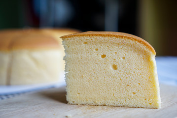 Fluffy cheese cake, a pieces of sponge cake with soft texture. On wooden plate.