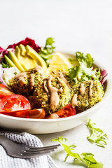 Baked falafel bowl with vegetable salad, tahini dressing and avocado.