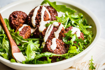 Beetroot Falafel with tahini dressing and arugula in a white bowl. Healthy vegan food concept.