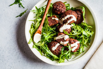 Beetroot Falafel with tahini dressing and arugula in a white bowl, top view. Healthy vegan food...