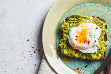 Avocado and poached egg toast on rye bread, top view.