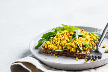 Tofu scramble toast with greens on rye bread. Healthy vegan food concept.