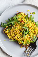 Tofu scramble toast with greens on rye bread, top view. Healthy vegan food concept.
