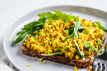 Tofu scramble toast with greens on rye bread. Healthy vegan food concept.