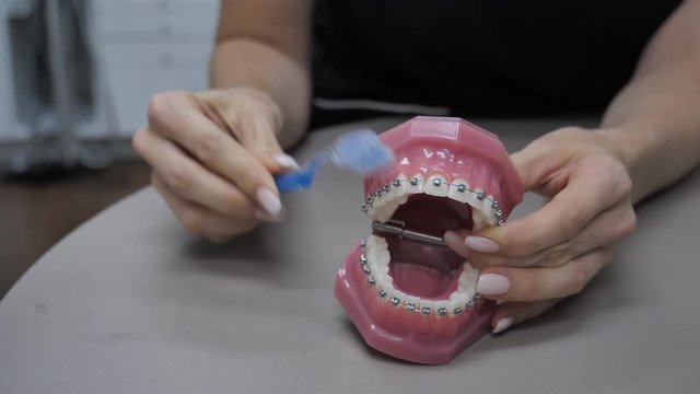 Woman showing how to brush teeth with braces