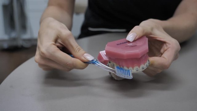 woman with toothbrush shows how to brush teeth with braces