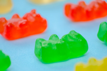 Lots of colorful multi-colored jelly bears on a blue background, macro