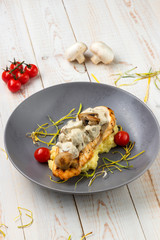 Grilled chicken breast in creamy mushroom sauce with delicate mashed potatoes and juicy cherry tomatoes, lunch menu of national food restaurant on white wooden background in rustic style