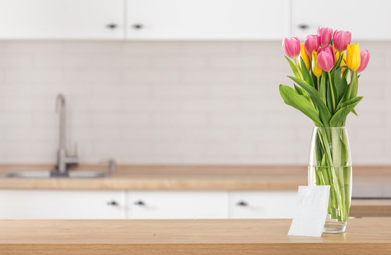 Bouquet Of Beautiful Tulips On Kitchen Table With Blank Sheet Of Paper For Your Message On Blur Kitchen Background With Place For Montage Product Display