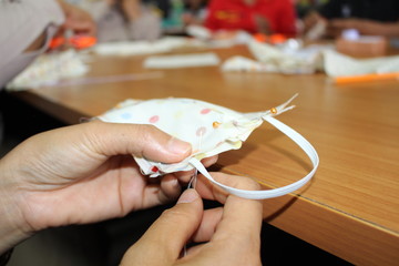 Young women helping to sew nose masks to prevent covic disease 2019