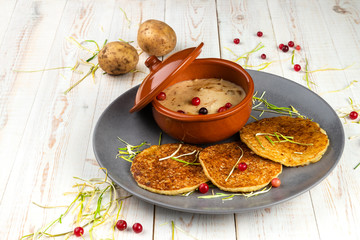 potato pancakes and machanka with cranberries on white wooden background in rustic style, example of menu in traditional belarusian restaurant, horizontal photo