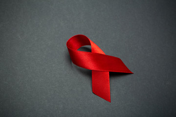 The red ribbon on a dark gray background. The symbol of The World AIDS Day or cancer or HIV Awareness Month and concept of healhcare. Copy space