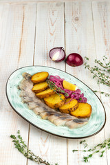 close-up homemade salting herring with baked potatoes, red onion rings in oil and rye bread...