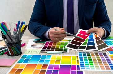 Graphic designer choosing a color from a sampler at office. Man hands choosing a color from an...