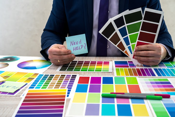 Graphic designer choosing a color from a sampler at office. Man hands choosing a color from an...