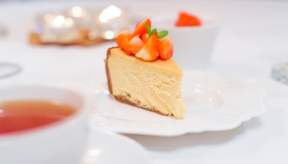 Fresh strawberry cheesecake on a ceramic plate on a white festive table
