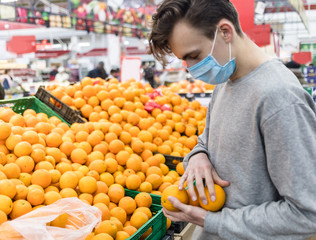 Young man wearing disposable medical mask shopping in supermarket during coronavirus