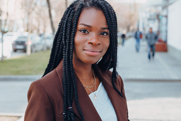 Close up portrait of a beautiful young african american woman with pigtails hairstyle in a brown...