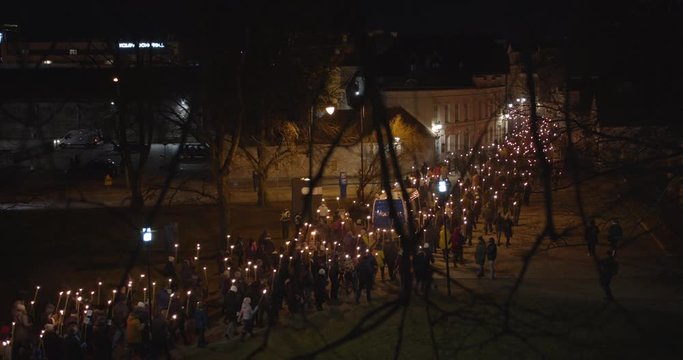 Crowd of people walking with burning torches on torchlight procession at night