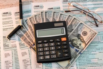 1040 tax form on desk with pen calculator and us dollar. business concept