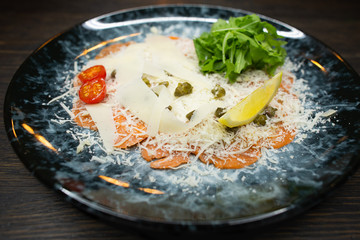 salmon carpaccio with cheese, a slice of lemon and cherry tomatoes and lettuce. pickled salmon