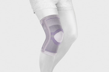 Knee Support Brace on leg isolated on white background. Orthopedic Anatomic Orthosis. Braces for knee fixation, injuries and pain. Orthotics. Foot orthosis. Knee Joint Bandage Sleeve. Elastic Sports 