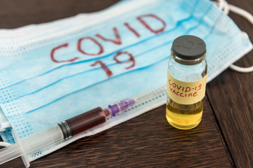 COVID-19 coronavirus ampoule with a vaccine, infected blood in the syringe, medical mask. Dangerous diseases and viruses