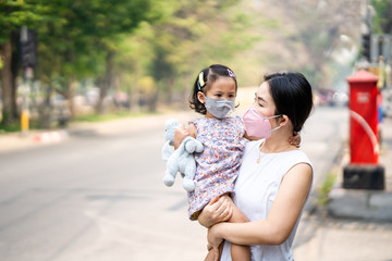 Mum and daughter standing along the road wearing face mask protect filter against air pollution (pm2.5) and Covid 19.