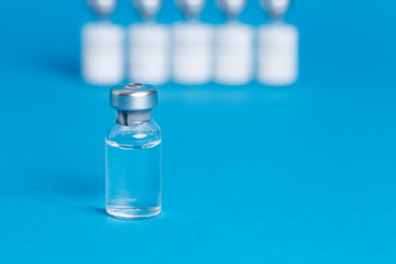 Closeup vaccine bottle on blue isolated background. Lack of coronovirus vaccine.