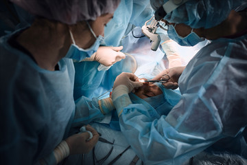 Medical team in the operating room, dark background. The theater of the operating room, an international team of professional doctors in a modern operating room are conducting an operation. Saving