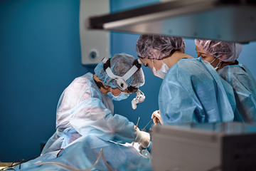 Surgeons and paramedic in mask and operating patient, a professional team of doctors in a modern...