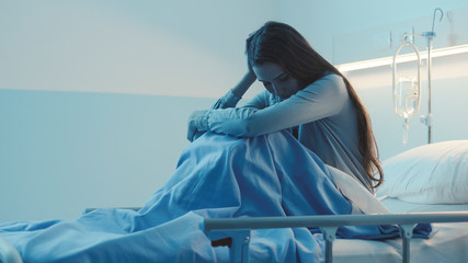 Sad female patient lying in a hospital bed at night