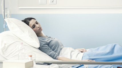 Young woman lying in a hospital bed with IV drip