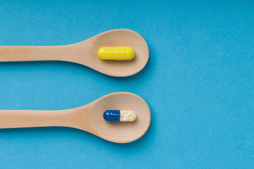 Capsules in a wooden spoon. Flat lay, top view. Copy space .