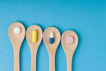 Medical pills with a wooden spoons on a blue background. Close up