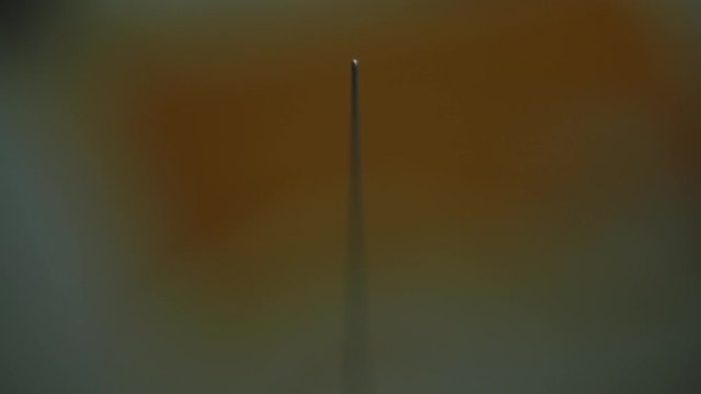 The Tip of Needle Comes Out in the Orange Background Factory Production Abstract