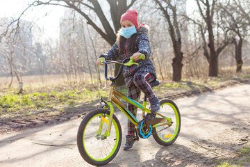 Fototapeta premium 7 years old happy Little girl child ride bicycle in the park at home and wearing protection mask for protect pm2.5 and Coronavirus Covid-19 Pandemic virus symptoms.Sport exercise for health.