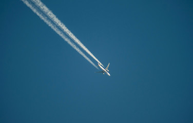 Jet airliner flying high in the sky leaves contrails in the clear blue sky