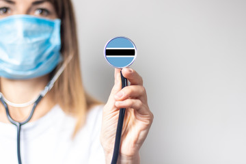 female doctor holding a stethoscope on a light background. Added flag of Botswana. Concept...