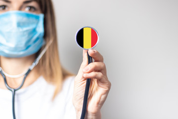 female doctor holding a stethoscope on a light background. Added flag of Belgium. Concept medicine,...