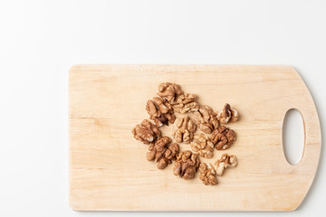Peeled walnuts on a wooden cutting board on a white background