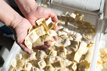 process of production of ravioli, tortellini and cappelletti, typical Italian fresh pasta - hands of the chef showing the freshly produced ravioli
