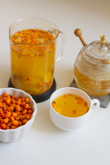 Vitamin useful sea buckthorn tea in a glass teapot with fresh sea buckthorn berries, orange, cinnamon sticks and honey. The concept of rest, relaxation. top view with a copy of the space